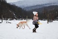 Half breed shepherd and Husky gets along well with child. Winter holidays in village in fresh air. Little girl in warm knitted hat