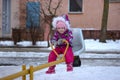 A little girl in a warm pink winter jacket rides on a swing at the playground Royalty Free Stock Photo