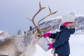 Girl feeding reindeer in the winter Royalty Free Stock Photo