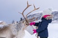 Girl feeding reindeer in the winter