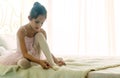 Little girl was sitting the white bed and tying ballet shoes for ballet class practice with the light from window Royalty Free Stock Photo