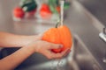 Little girl washing bright orange vegetable in a washer Royalty Free Stock Photo