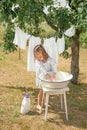 A little girl is washing  linen in the garden under a tree and hanging snow-white pure clothes to dry in the fresh air. Royalty Free Stock Photo