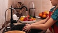 Little girl washing a red bellpepper at the kitchen sink