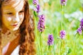 little girl watching a bee pollinate wild flowers in a field Royalty Free Stock Photo