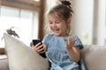Little girl watching cartoons on smartphone laughing having fun indoors