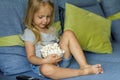 Little girl watching TV. Happy cute little girl holding a bowl with popcorn Royalty Free Stock Photo