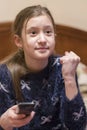 Little girl is watching tv in her bed. Little girl watching tv. Teen girl eating popcorn in front of the TV. toned. vertical photo Royalty Free Stock Photo