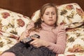 Little girl watching TV lying on bed with remote control in hand. toned Royalty Free Stock Photo