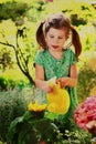 Little girl with water can watering flowers in garden Royalty Free Stock Photo