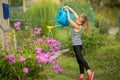 Little girl watering flowers near the house . Royalty Free Stock Photo