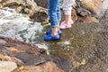 Little girl wearing blue slippers standing on the rocks near a sea. A child in blue shoes perches on the shore Royalty Free Stock Photo