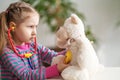 Little girl wearing in everyday clothes, using stethoscope on teddy bear Royalty Free Stock Photo