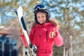 Winter vacation. Girl in goggles and helmet with skis standing outdoors smiling happy showing thumb up close-up blurred