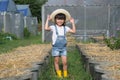 Little girl wearing a hat helps her mother in the garden, a little gardener. Cute girl playing in the vegetable garden Royalty Free Stock Photo