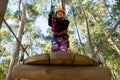 Little girl wearing helmet holding rope and standing on wooden platform Royalty Free Stock Photo