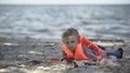 Little girl wearing life jacket lying on shore, survived plane crash, disaster Royalty Free Stock Photo