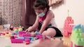 Little Girl Wearing Mask Playing With Colorful Lego Dices.