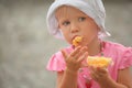 Little girl wearing panama hat is eating orange