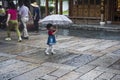 A little girl in a red blouse, blue skirt and white stockings with a plaid umbrella in the scenic area Royalty Free Stock Photo