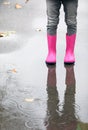 Little girl wearing rubber boots standing in puddle on rainy day, focus of legs. Royalty Free Stock Photo