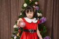 A little girl wearing a Santa Claus costume playing in front of a Christmas tree Royalty Free Stock Photo