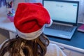 A little girl wearing a Santa hat in front of a laptop looking for Christmas ideas on the internet Royalty Free Stock Photo