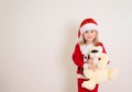 Little girl wearing a santa hat holding a toy bear isolated on white background. Merry Christmas and Happy New Year Royalty Free Stock Photo