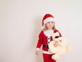 Little girl wearing a santa hat holding a toy bear isolated on white background. Merry Christmas and Happy New Year Royalty Free Stock Photo