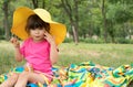 Little girl wearing straw hat eating candy on summer picnic. Royalty Free Stock Photo