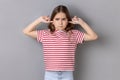 Little girl wearing striped T-shirt covering ears not to hear advice, ignoring upbringing, parenting Royalty Free Stock Photo