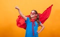 Little girl wearing superman costume ready to fly off in studio over yellow background