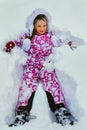 Little girl wearing winter clothes lying in snow