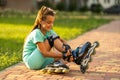little girl wears roller skates on beautiful summer day in a park