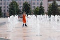 Little girl in wet dress roller skates in fountain in summ