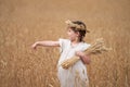 A little girl in a wheat field. She is pointing to an ear with her hand, holding an armful of grain in her other hand. Royalty Free Stock Photo