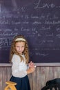 little girl in a white blouse with long hair writes with chalk on black chalkboard. back to school.Elementary education Royalty Free Stock Photo