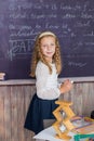 little girl in a white blouse with long hair writes with chalk on black chalkboard. back to school.Elementary education Royalty Free Stock Photo