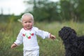 little girl in white clothes plays with black dog. Communication of children and animals. Good home dog outdoor