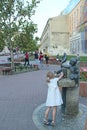 Little girl in white dress is naught with water in city statue fountain