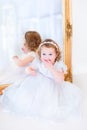 Little girl in a white dress next to a mirror Royalty Free Stock Photo