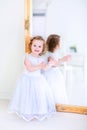 Little girl in a white dress next to a mirror Royalty Free Stock Photo