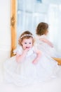 Little girl in a white dress next to a mirror Royalty Free Stock Photo