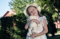 Little girl in a white dress and panama with a soft rabbit toy portrait on a foliage background