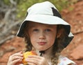 A Little Girl in a White Hat Eating a Peach Royalty Free Stock Photo