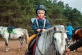 Little girl on a white pony on a background of nature. Jockey, hippodrome, horseback riding Royalty Free Stock Photo