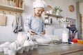 Little girl in a white shef hat cook the dough for cookies