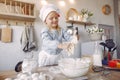 Little girl in a white shef hat cook the dough for cookies