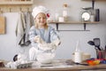 Little girl in a white shef hat cook the dough for cookies