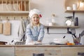 Little girl in a white shef hat cook the dough for cookies